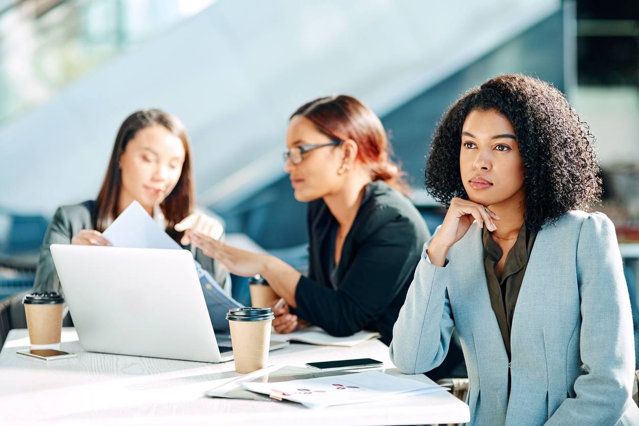 iStock-1074890606 employee looking off in the distance while 2 coworkers talk behind her